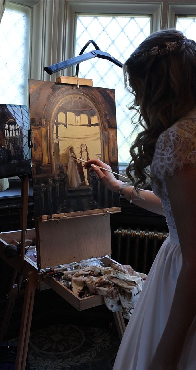 A bride in her dress adding her own brushstroke to the live painting at the easel
