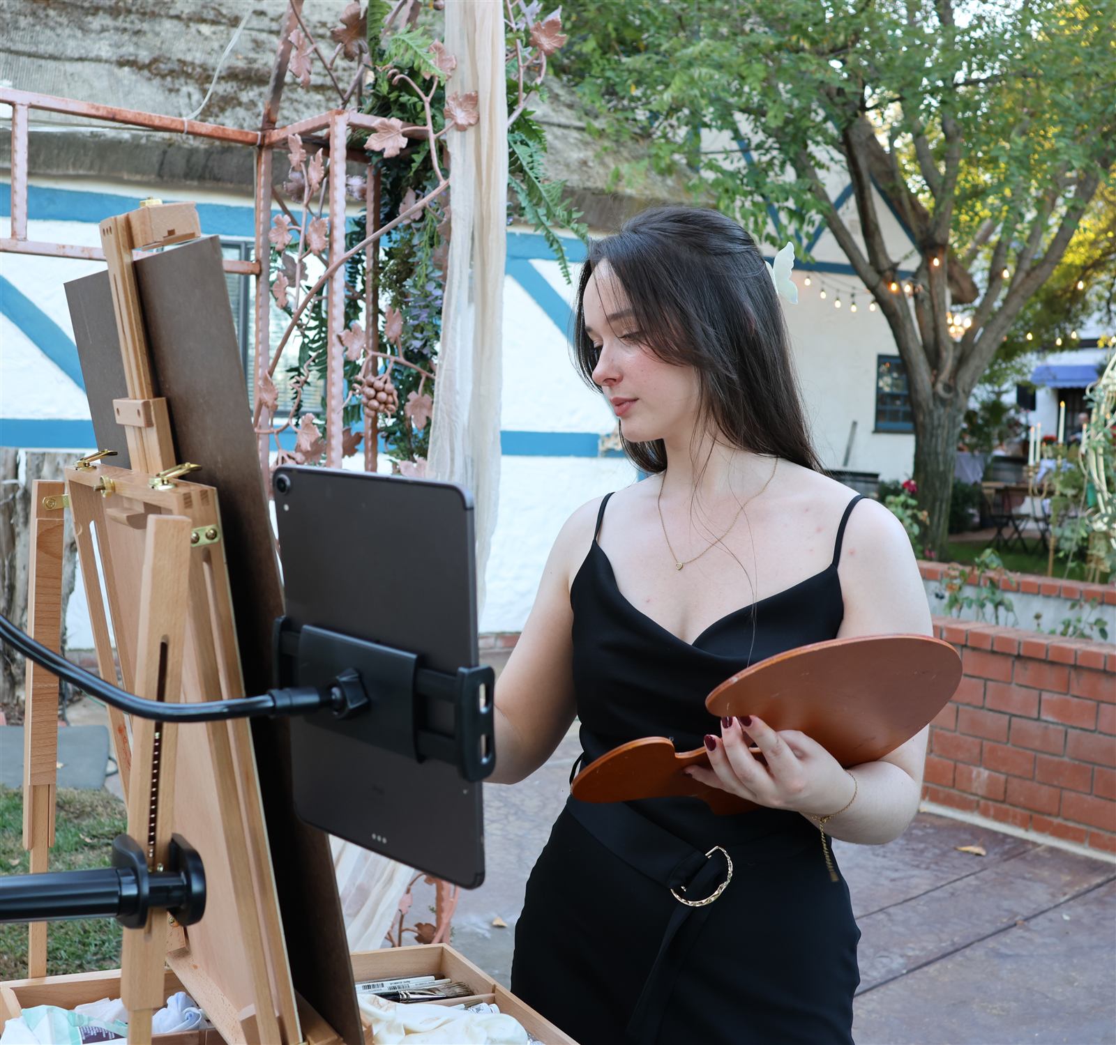 Caitlin at her easel with the reference photos on her iPad, planning the painting