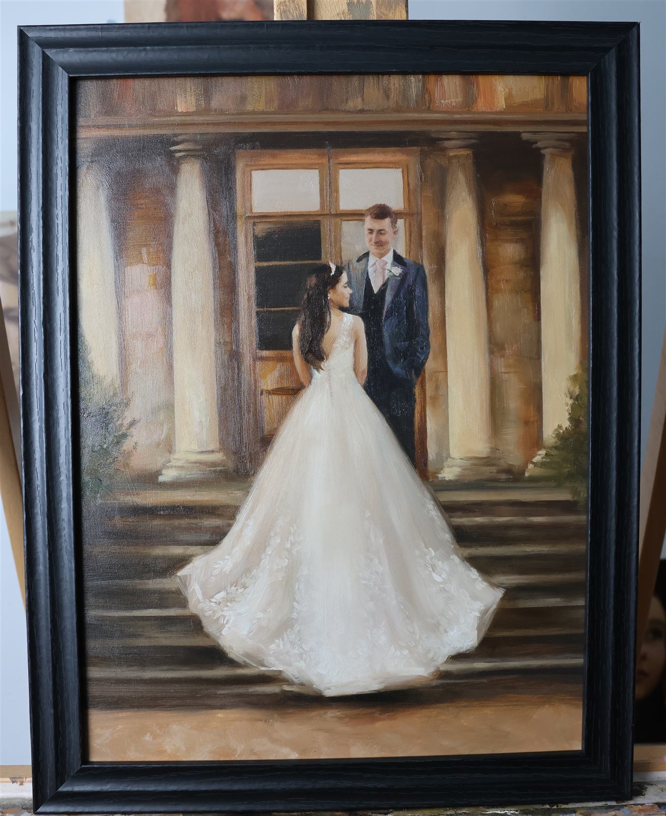 Black-framed oil painting of a bride in a flowing gown meeting the groom on the steps